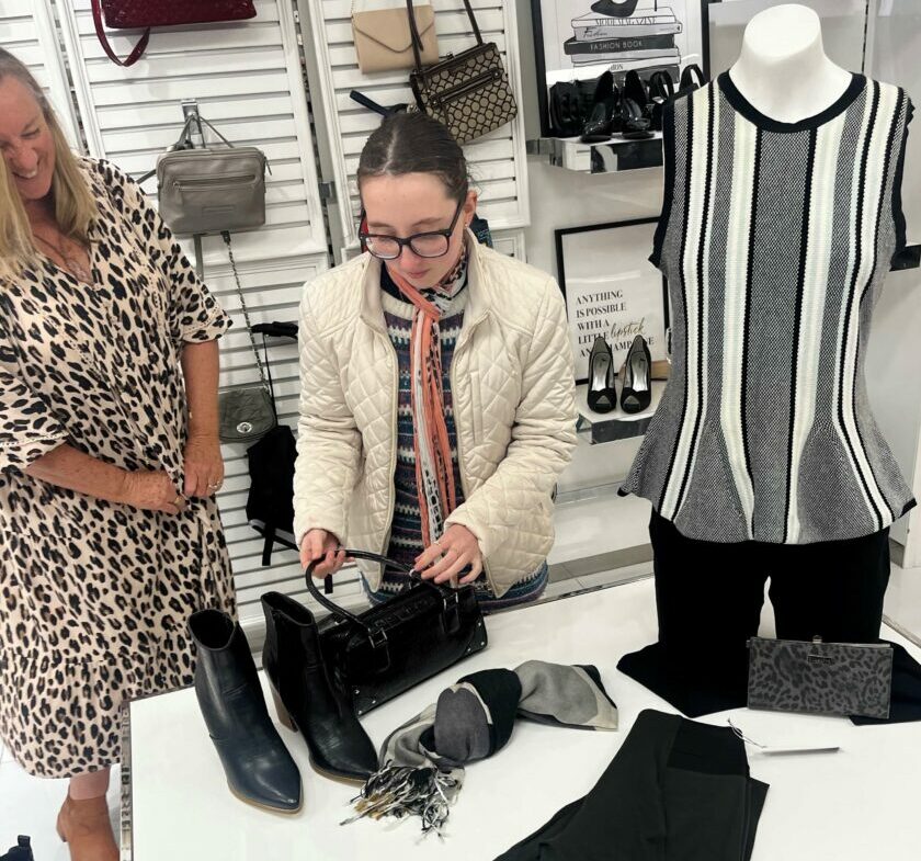Two people working with clothing and accessories in a store
