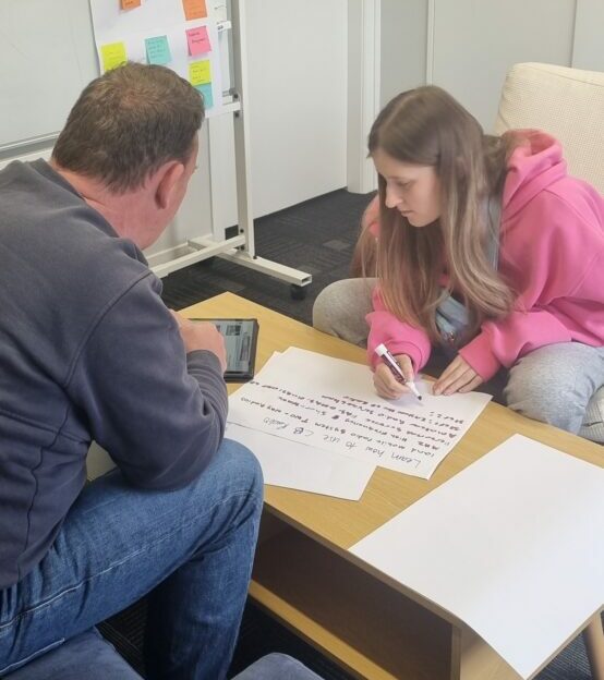 AJ and Madeleine sitting at a table writing during the work confidence programme