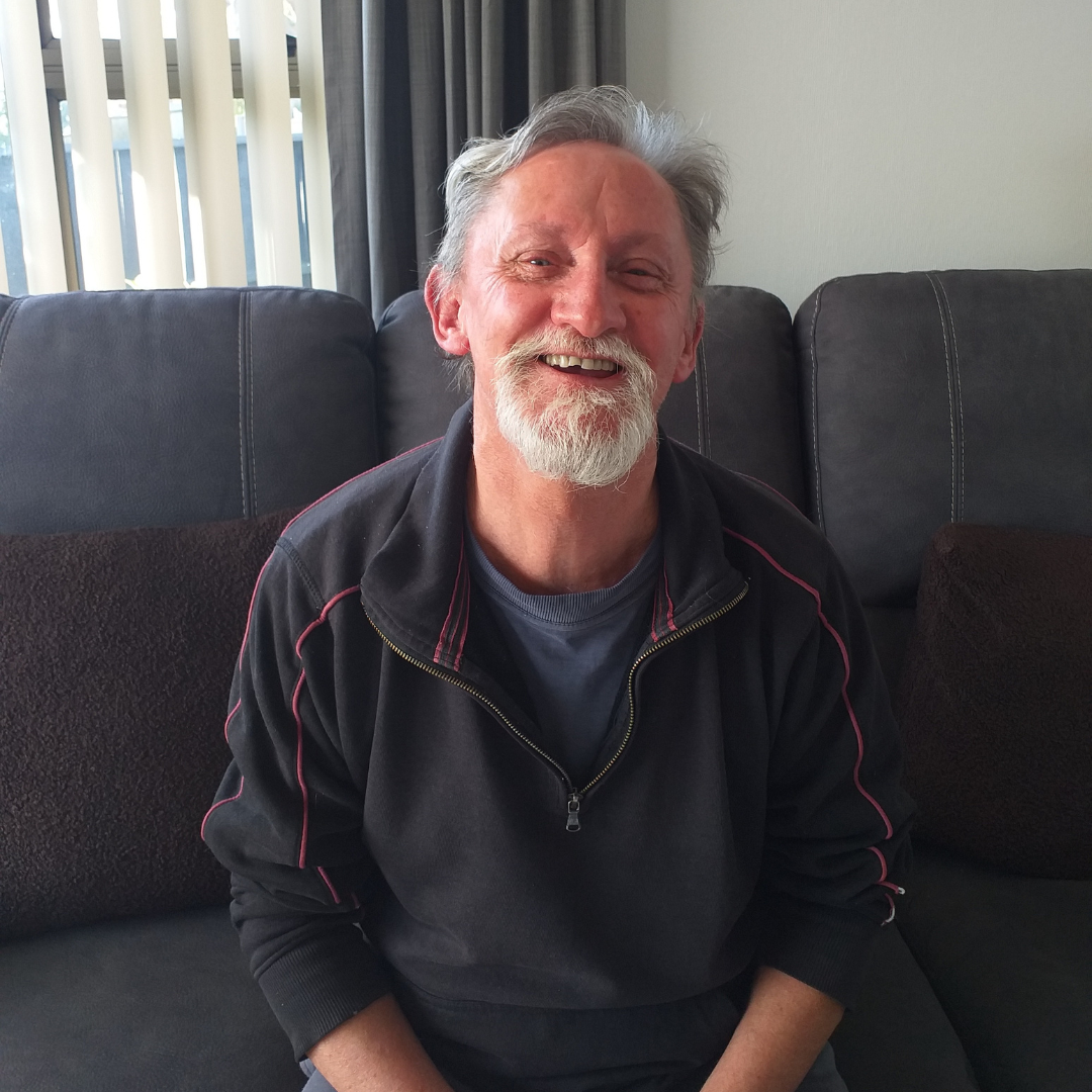 Momenta client Len sitting on a sofa wearing a black jumper